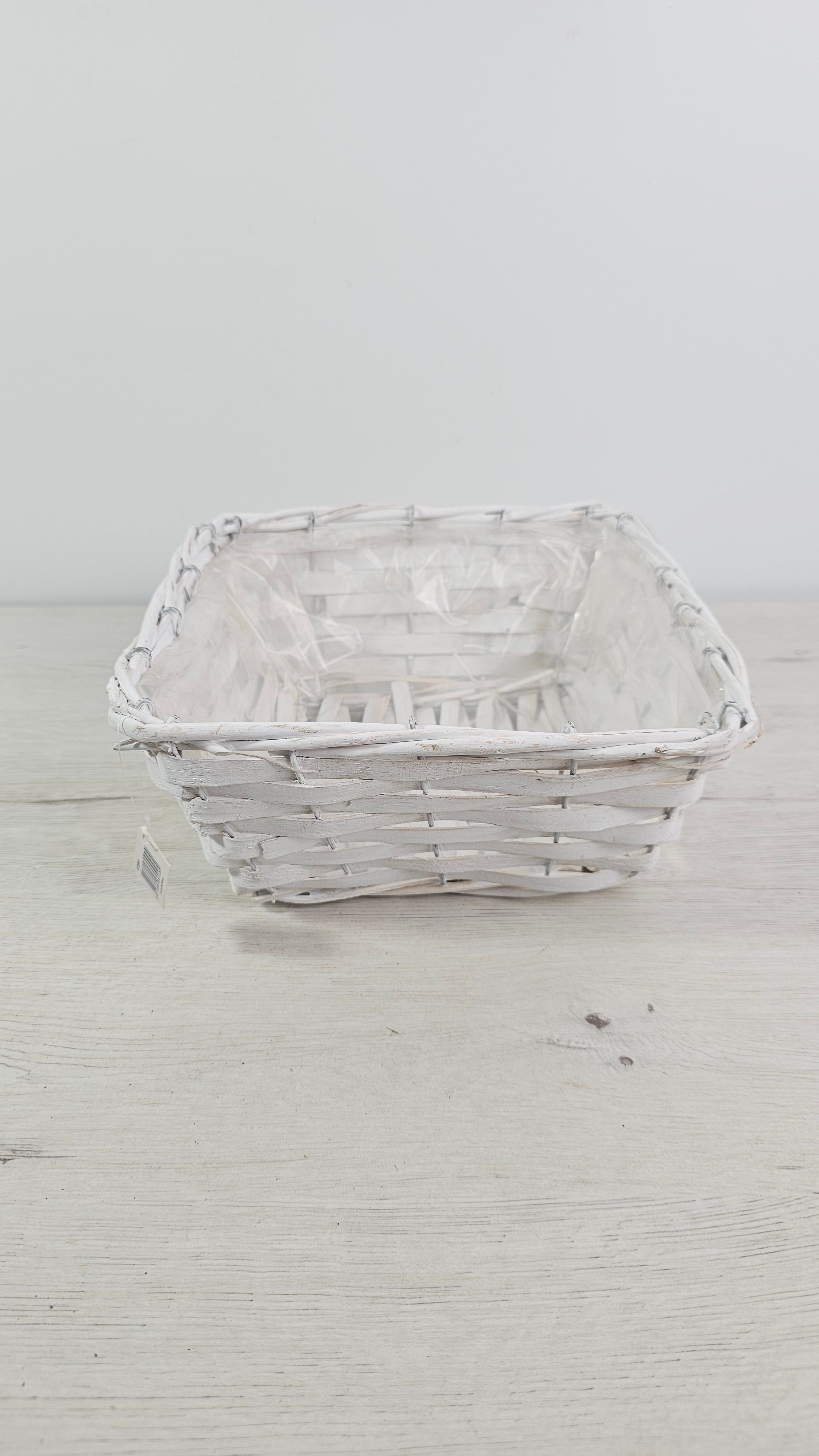 Cesta blanca cuadrada con forro interior de plástico para plantas y regalos.