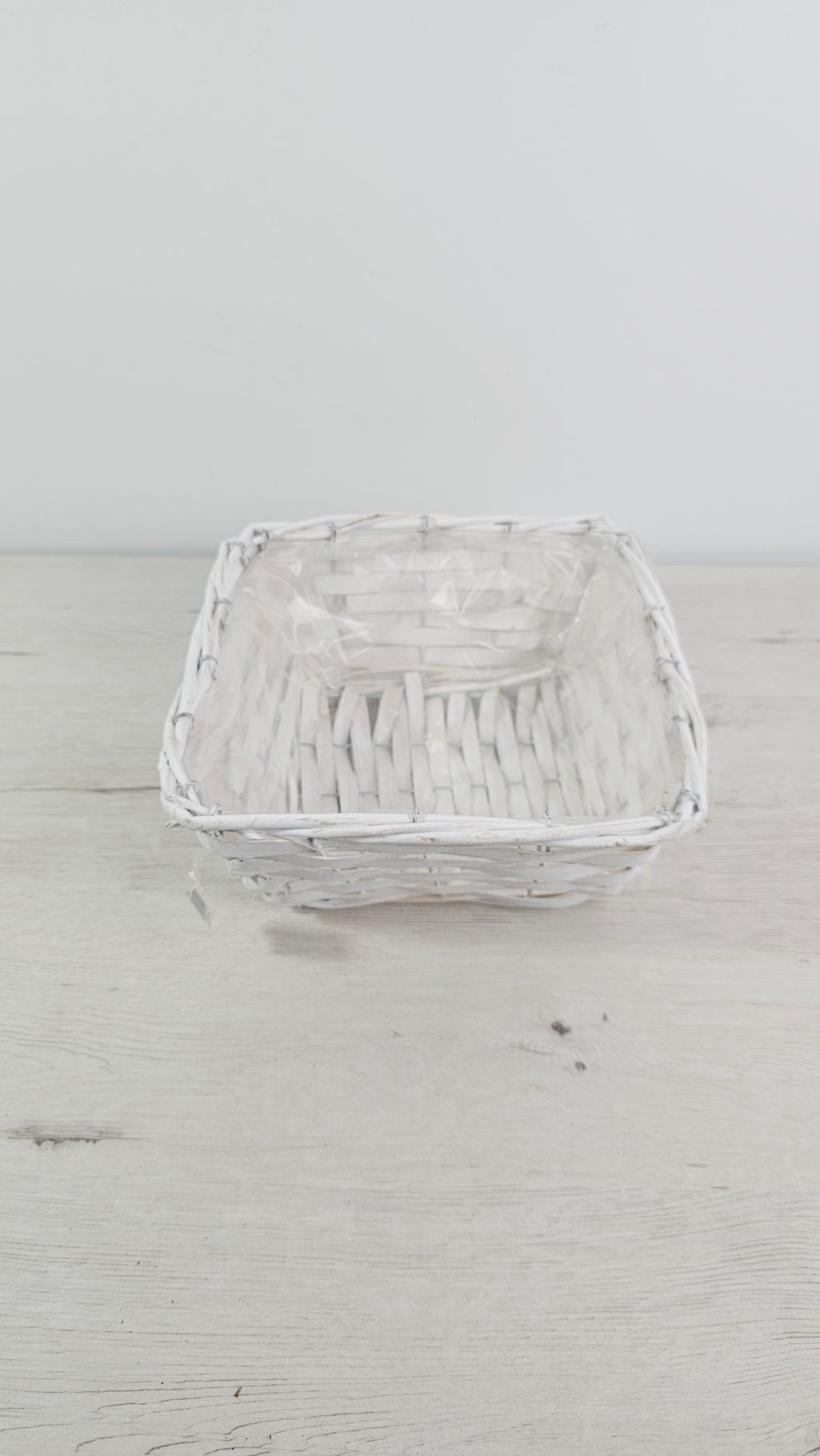 Cesta blanca cuadrada usada como cubremacetas para una planta de interior.
