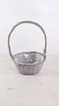 Cesta gris con asa alta y forro interior de plástico para plantas y regalos.  