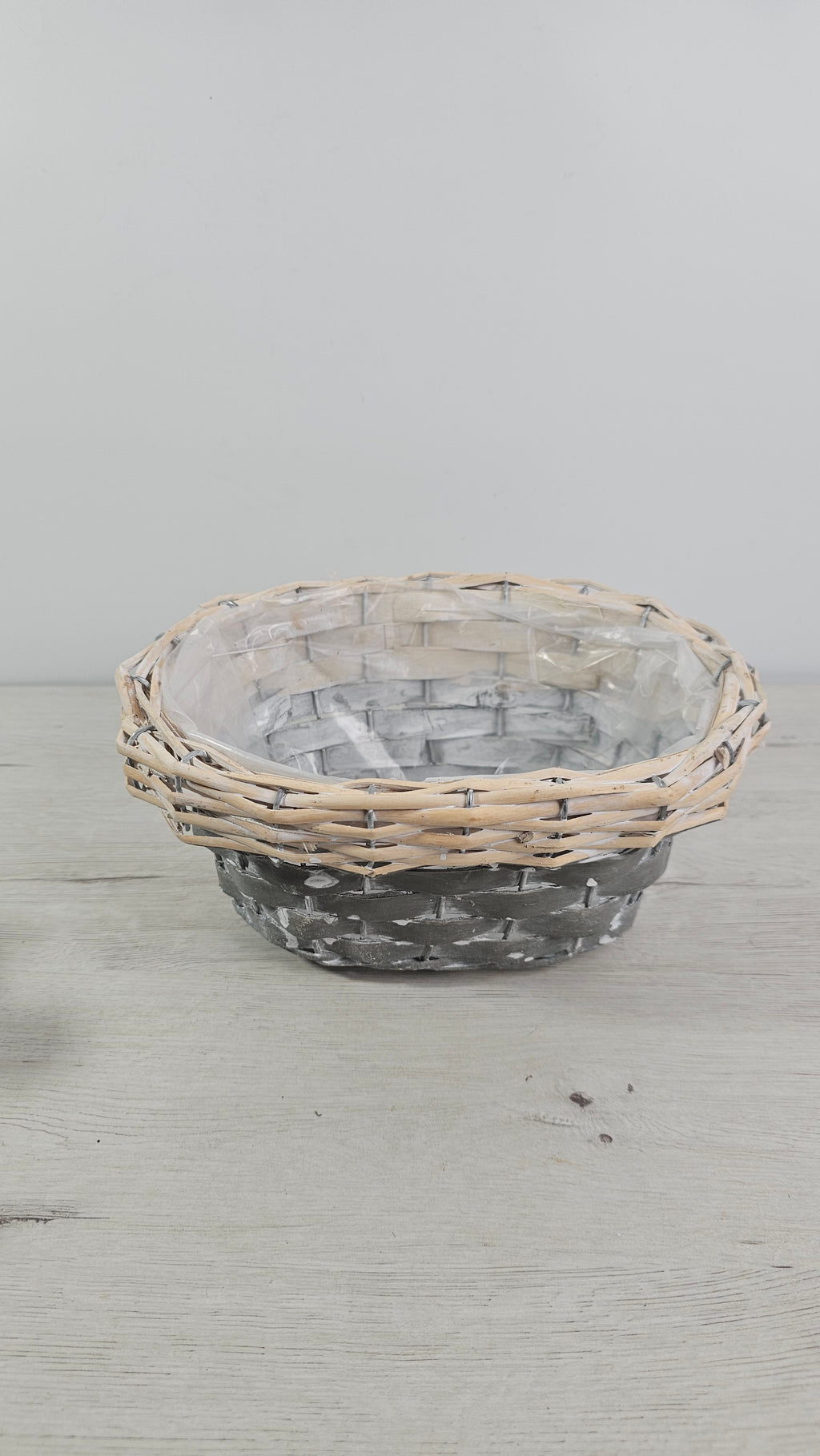 Cesta gris decorativa usada como cubremacetas para plantas de interior.  