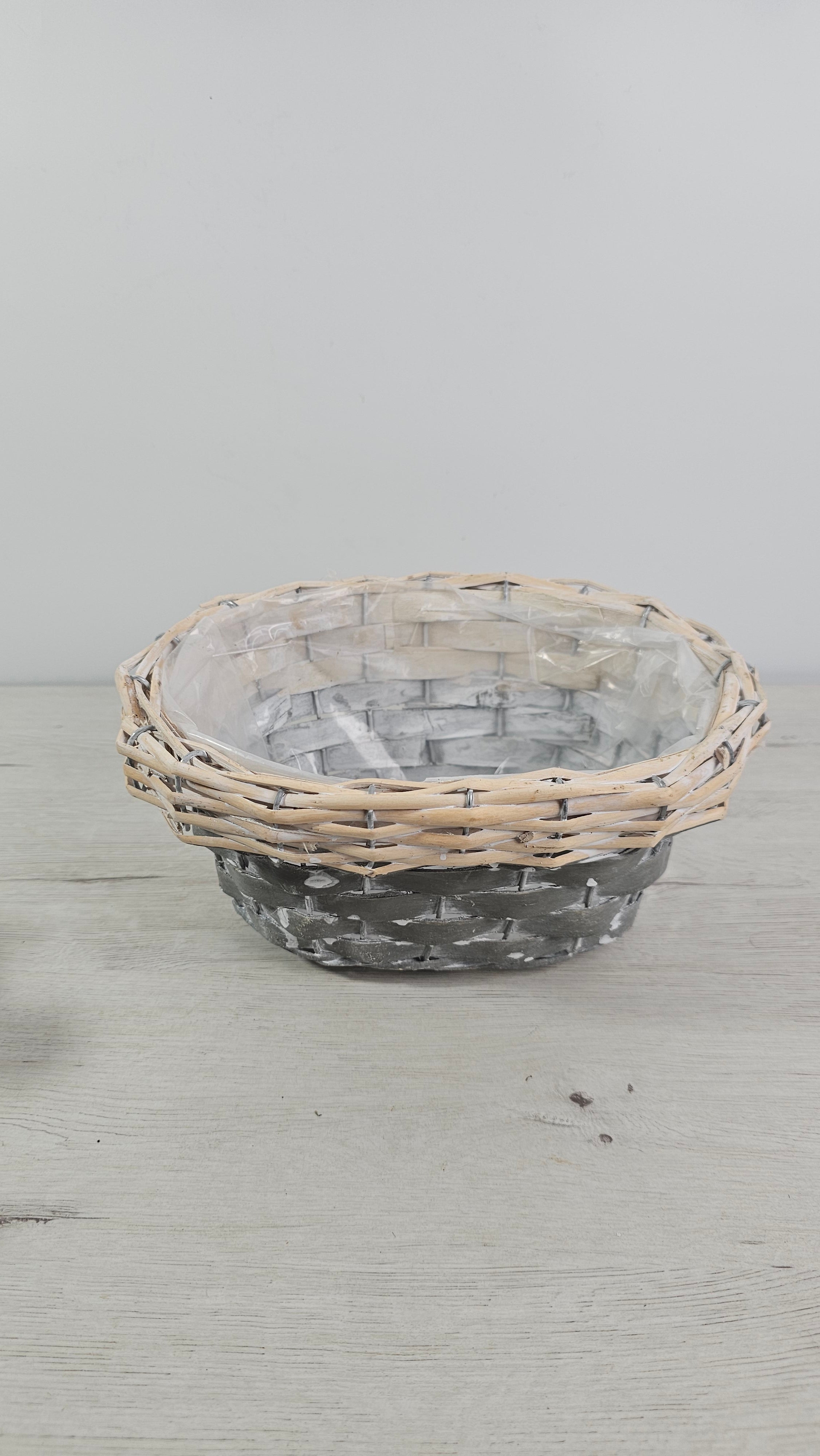 Cesta gris decorativa usada como cubremacetas para plantas de interior.  