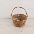 Cesta natural con asa trenzada de fibra, estilo artesanal.