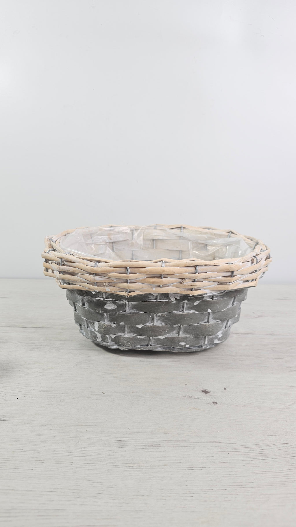 Cesta redonda gris y natural con forro interior de plástico. 