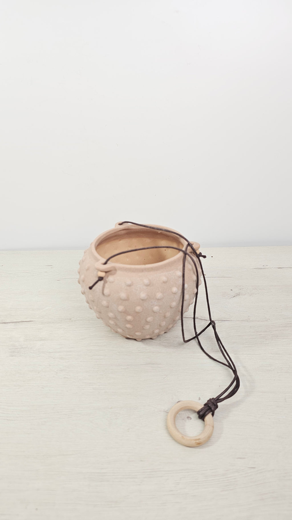 Maceta colgante con textura en relieve, ideal para plantas colgantes en casa.