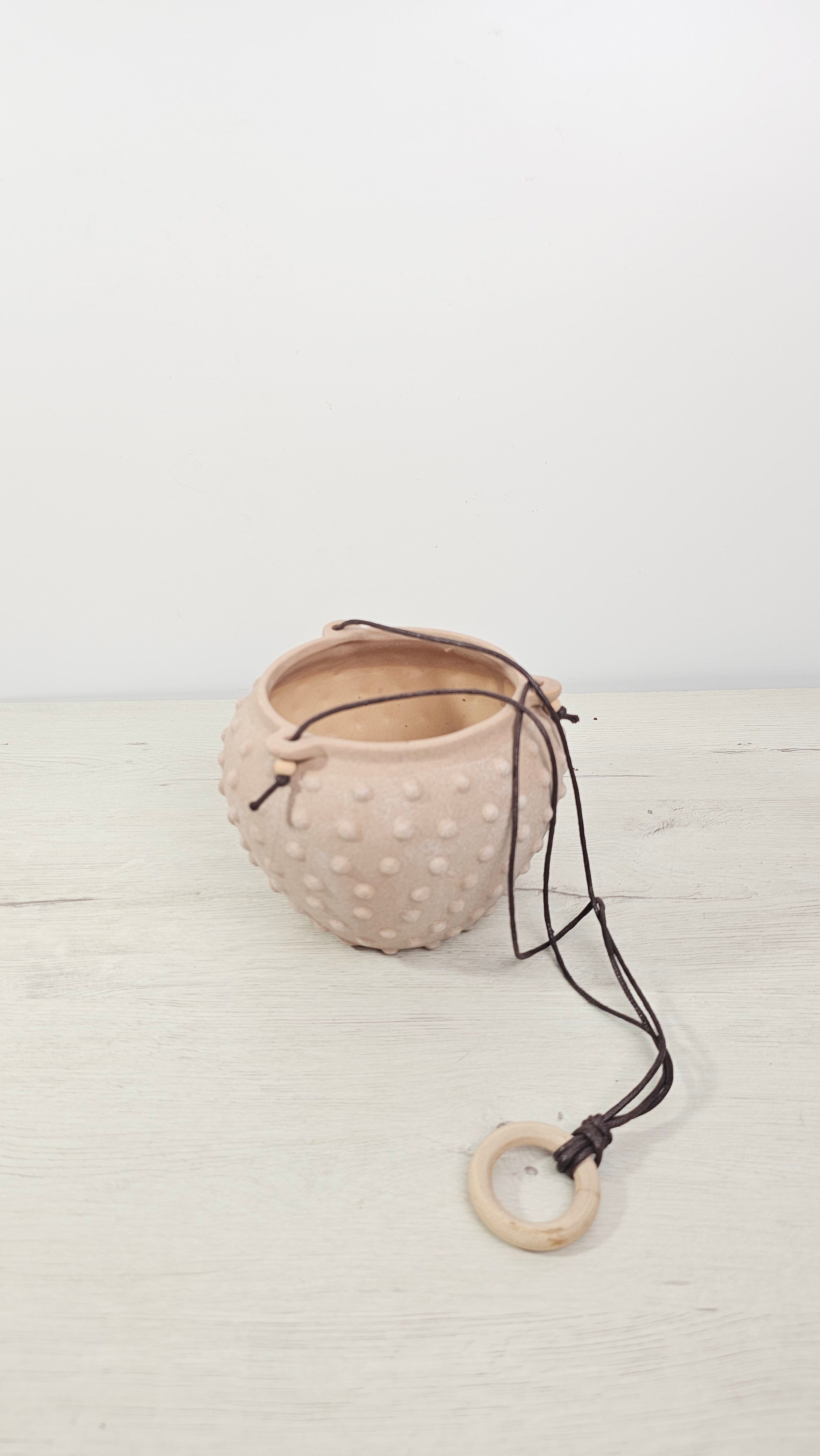 Maceta colgante con textura en relieve, ideal para plantas colgantes en casa.